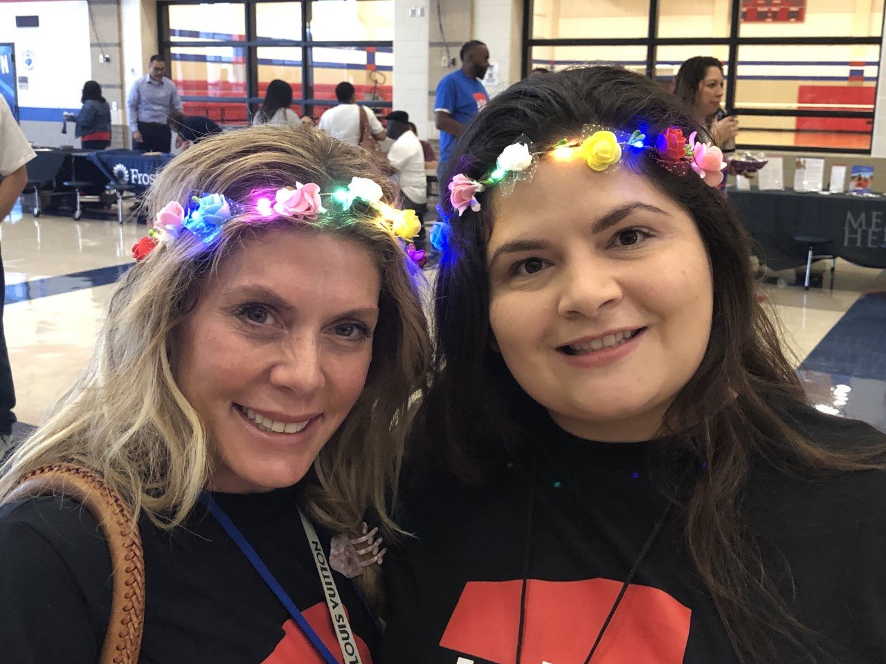 Tania Hausmann and Alicia Garcia of the Royal Early Childhood Center show off their flowers at the Royal ISD convocation. The flowers had small electric lights that helped brighten the event.